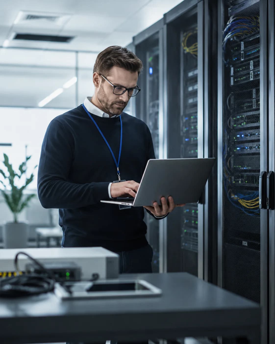IT-Fachmann mit einem Notebook im Serverraum, illustrative Darstellung